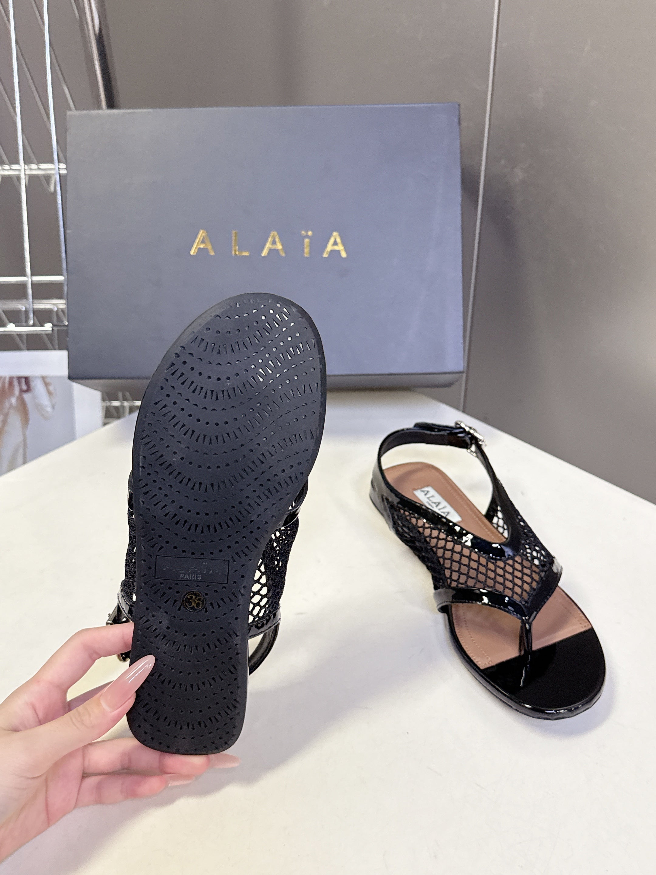 ALAIA 26S FLAT MESH THONG SANDALS IN BLACK PATENT CALFSKIN
