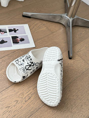 POOL GRAFFITI CROCS SLIDE SANDALS IN WHITE AND BLACK RUBBER