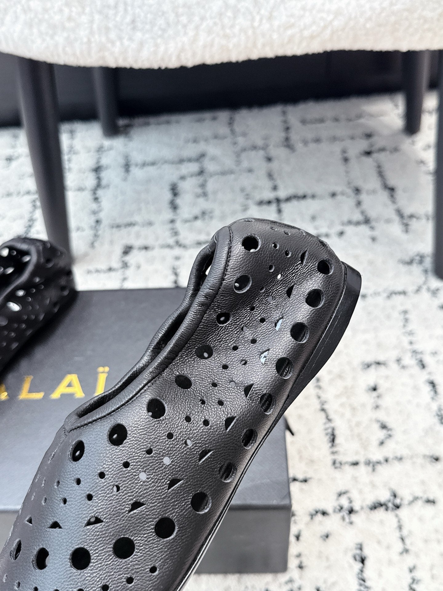 ALAIA 26S FLAT SLIP-ONS IN BLACK CALFSKIN WITH OPENWORK PATTERN