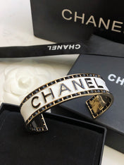 CHANEL 26S CHANEL LOGO ENAMEL CUFF BRACELET WITH BLACK TRIM IN GOLD METAL 630835